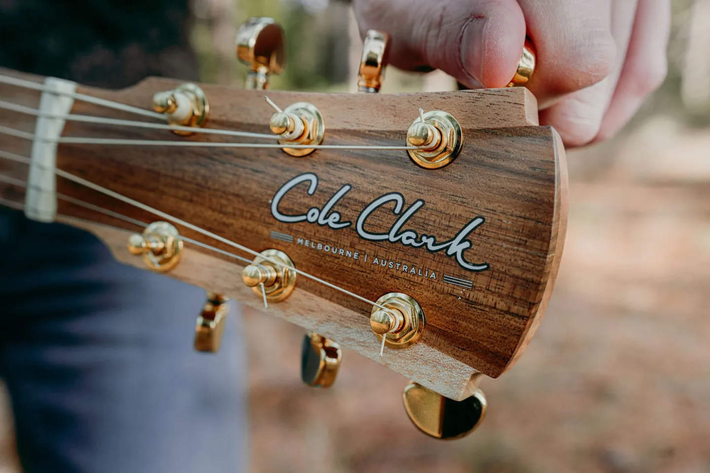 A hand tuning a Cole Clark guitar headstock