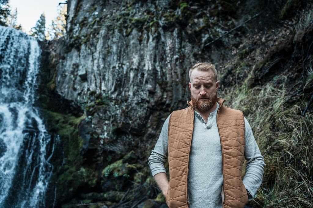 Roger standing before a waterfall in the woods
