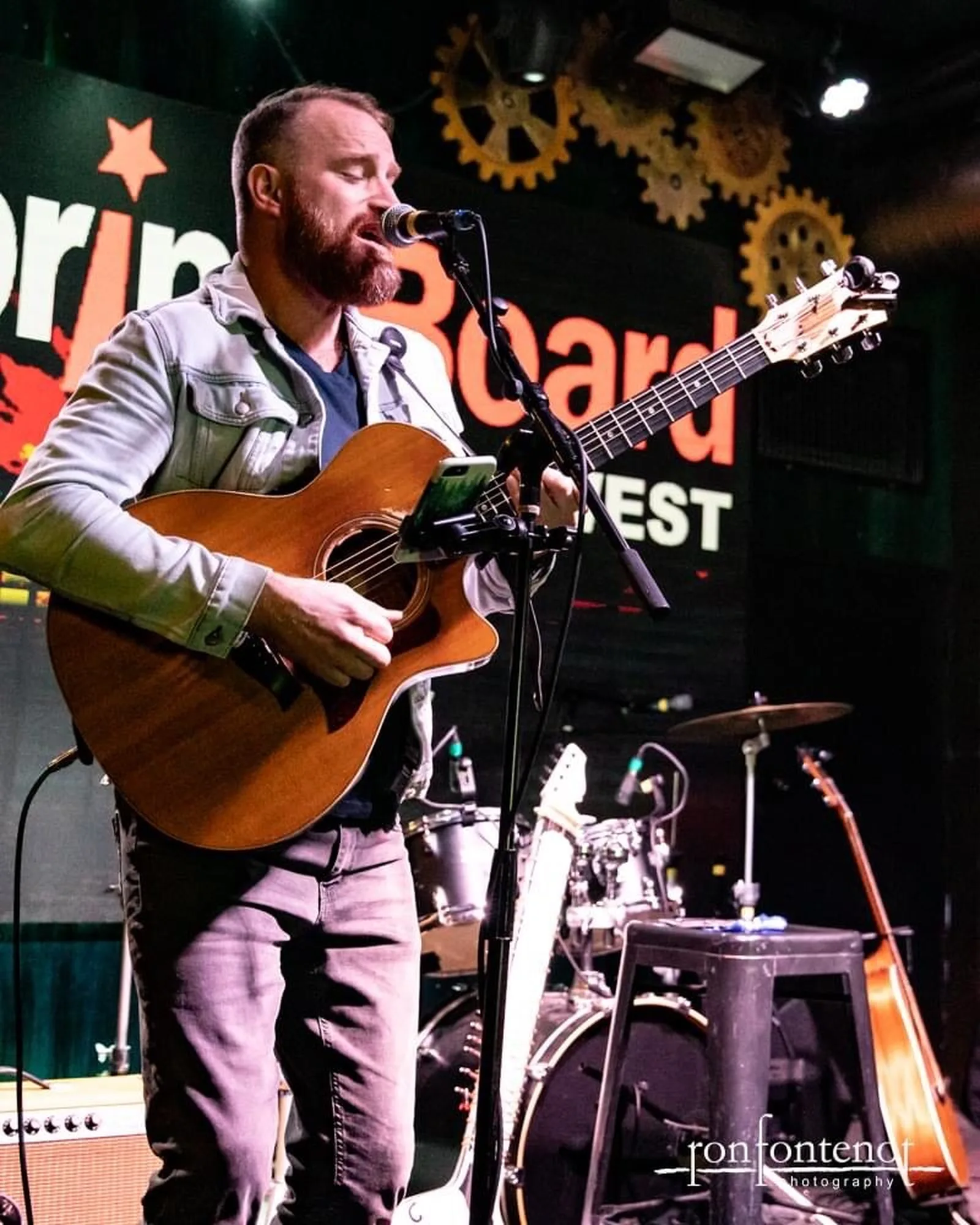 Roger playing acoustic guitar on stage at Springboard West