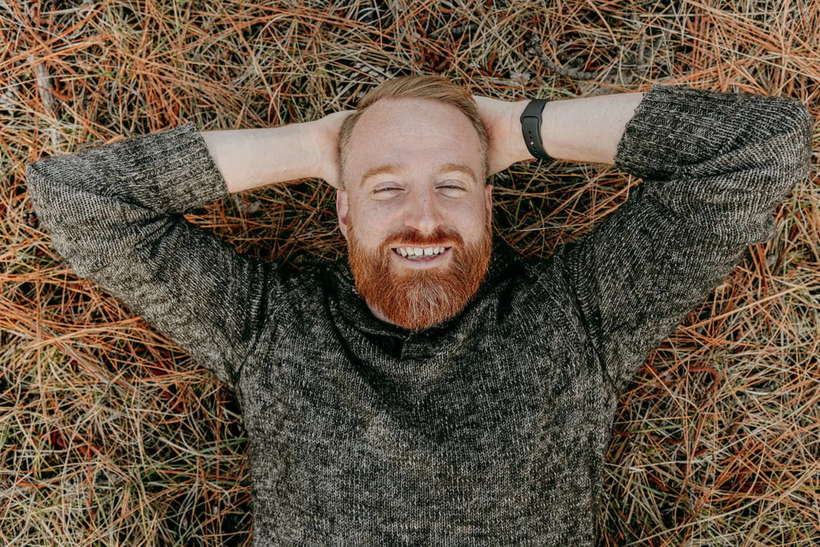 Roger Jæger lying in pine needles, laughing